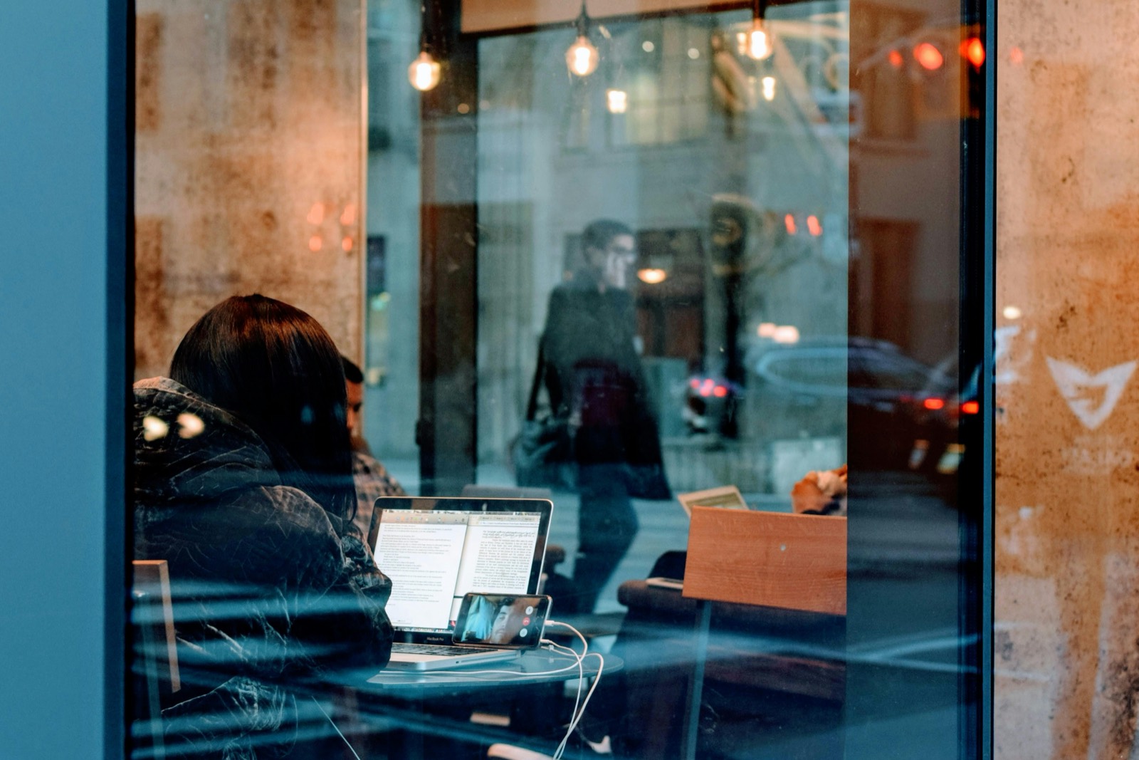A person working on a laptop inside a neighborhood cafe